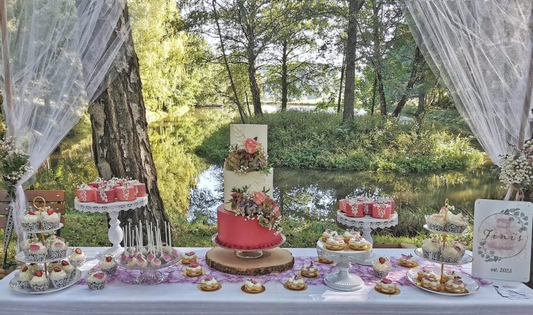 Festlich dekorierter Tisch mit einer Hochzeitstorte und verschiedenen Desserts.