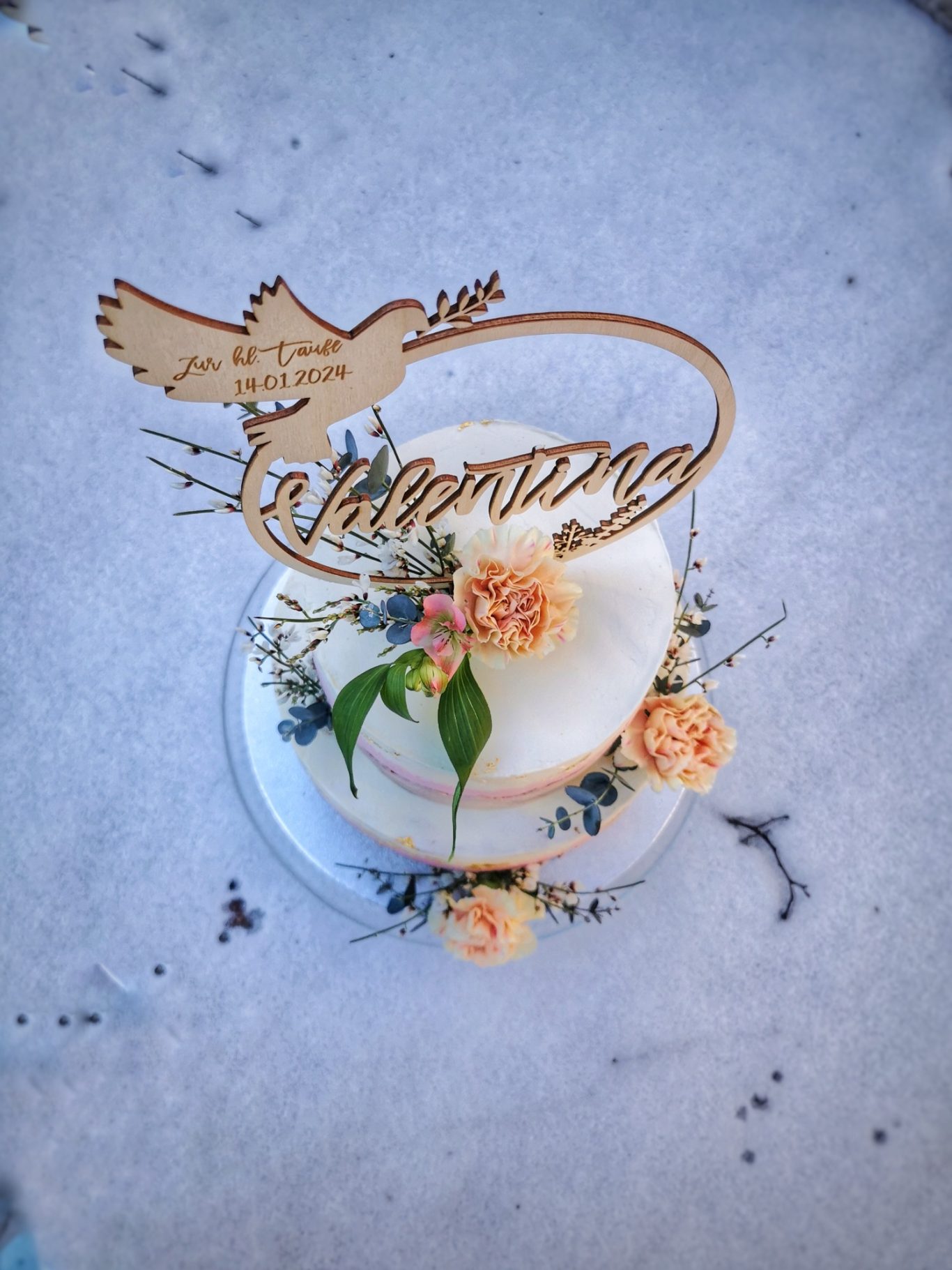 Tauftorte mit einer Taube und floralen Dekorationen, geschmückt mit Holzschriftzug.