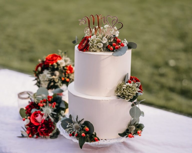 Zweistöckiger Hochzeitstorte mit floralen Dekorationen und Beeren.