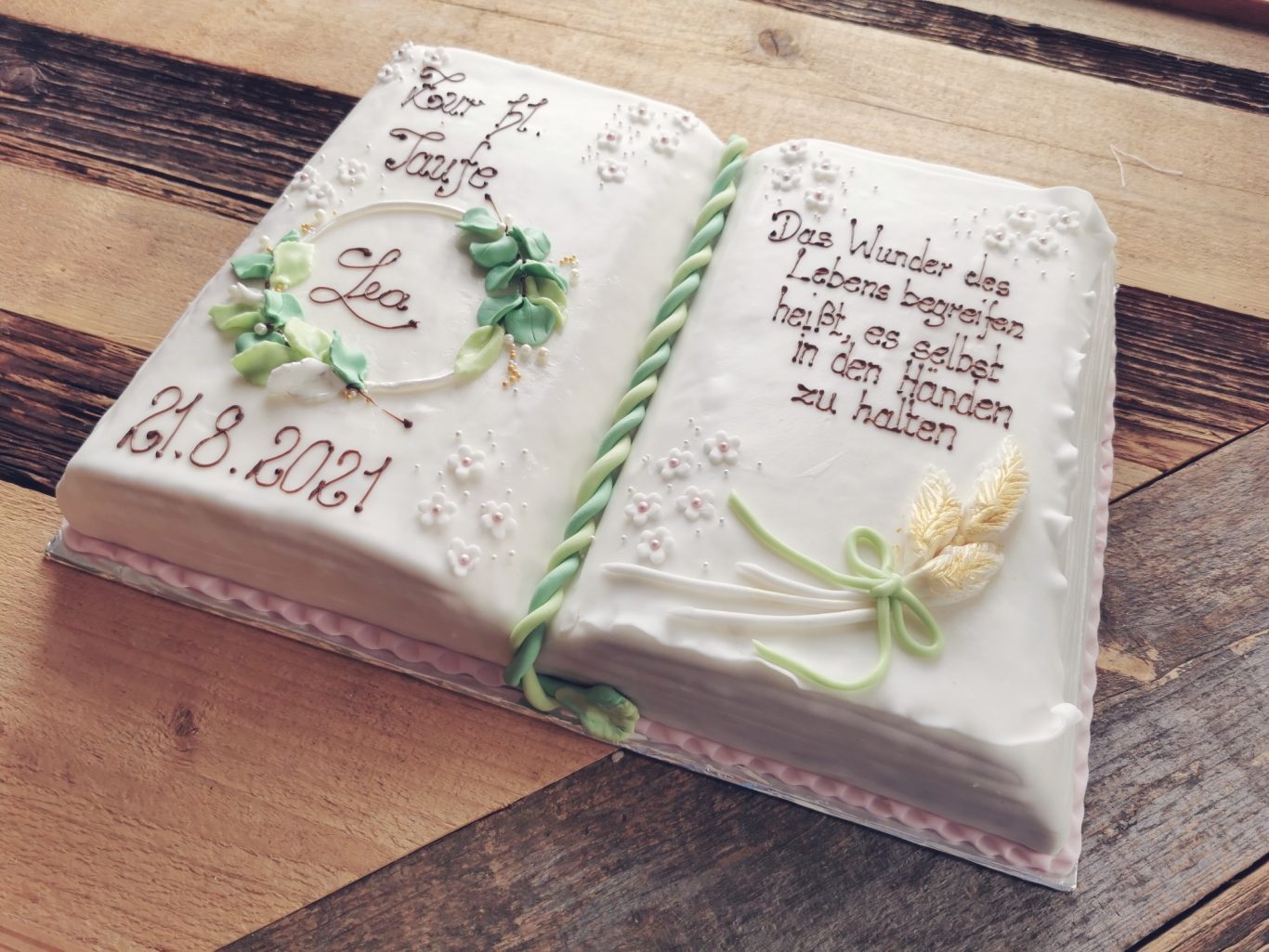 Eine Torte in Form eines aufgeschlagenen Buches mit Blumen und Schrift.