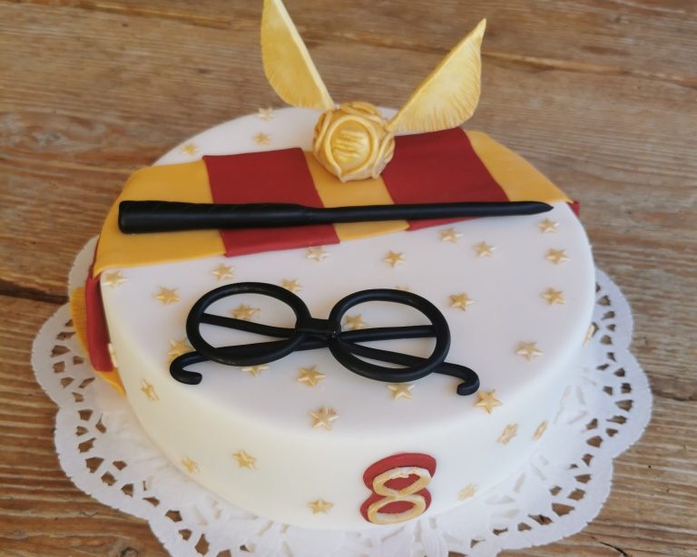 Torte mit Hogwarts-Design, Brille, Zauberstab und goldenem Schnatz.