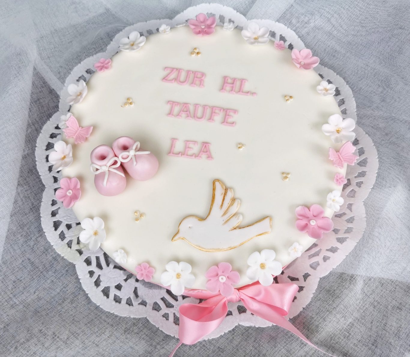 Torte zur Taufe von Lea, dekoriert mit einer Taube und rosa Details.
